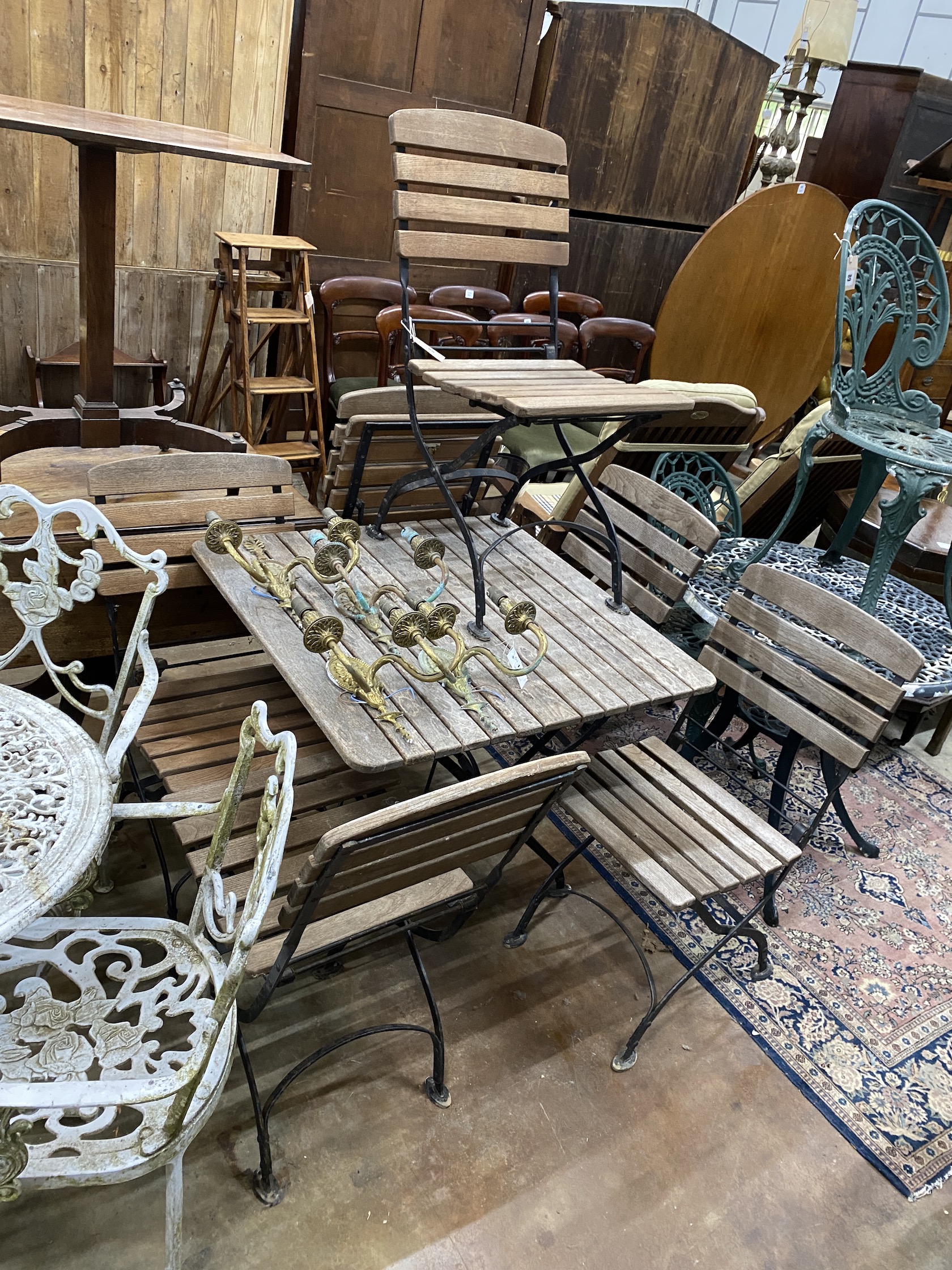 A square slatted teak and wrought iron folding garden table, width 80cm, height 73cm, and six folding chairs
